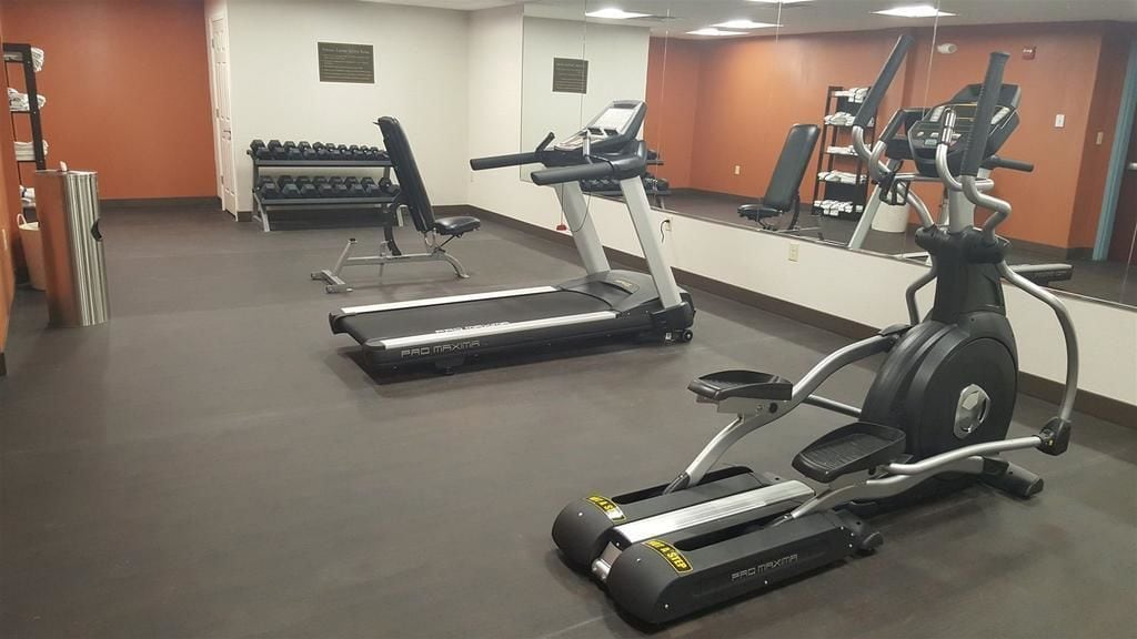 Un gimnasio con cintas de correr, una bicicleta estática y mancuernas.
