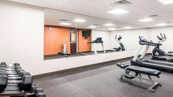 Un gimnasio con cintas de correr, elípticas y una zona de prensa de banca.