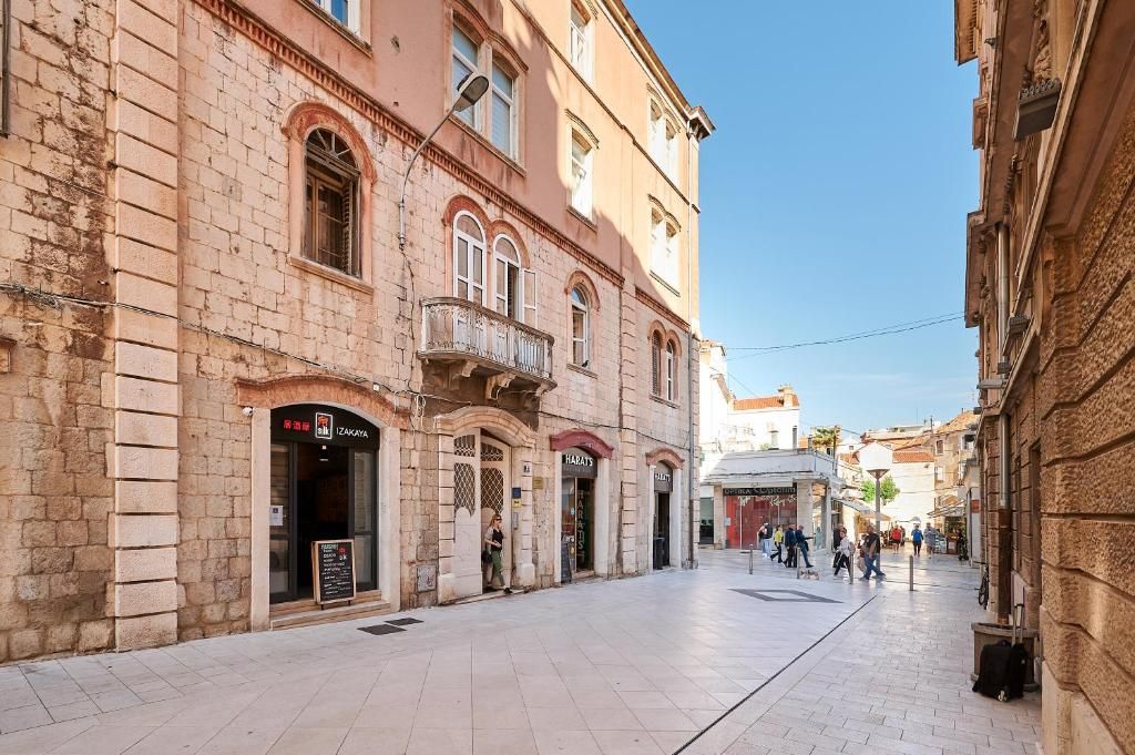 Calle peatonal con edificios históricos, cielo despejado y gente caminando.