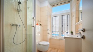 A modern bathroom with a glass-enclosed shower, a toilet, and a sink. - Marmont City Rooms (Split)