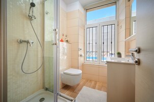 Uma casa de banho moderna com cabine de duche em vidro, sanita e lavatório.