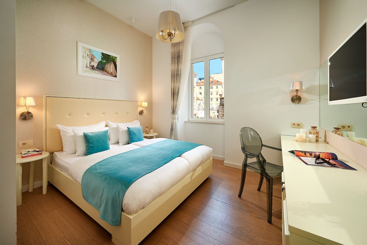 Une chambre d’hôtel bien rangée, avec un lit, des tables de chevet, un bureau et une chaise.