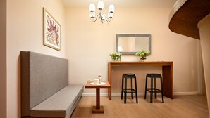 A small, cozy room with a bench, a wooden table with two stools, a mirror, and a chandelier. - Marmont City Rooms (Split)