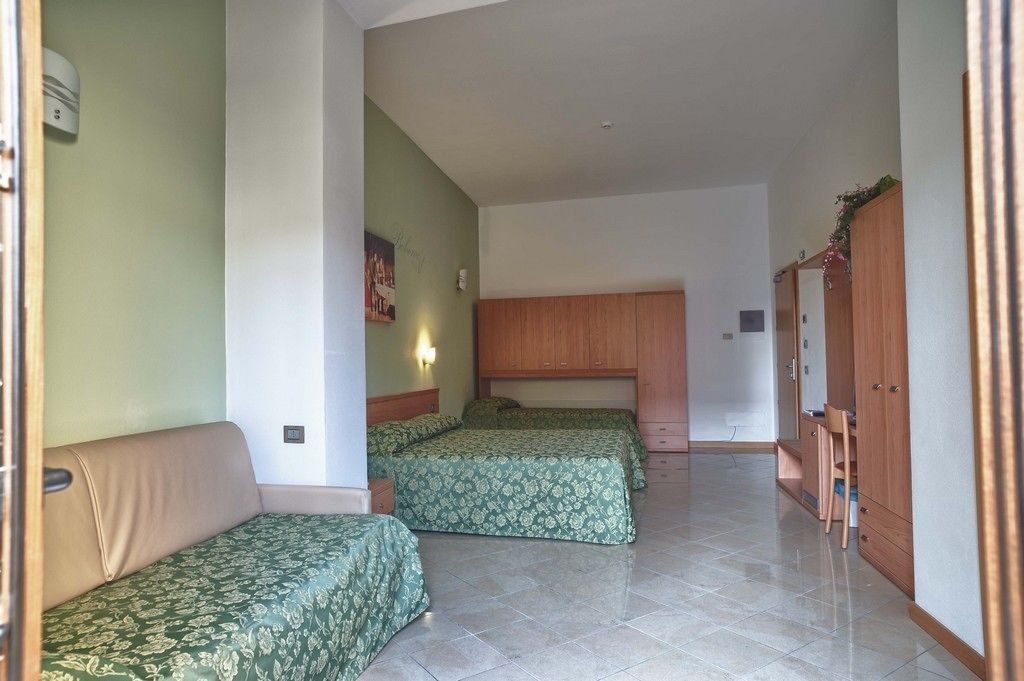 Una habitación con dos camas, un armario de madera y una pequeña zona de estar.