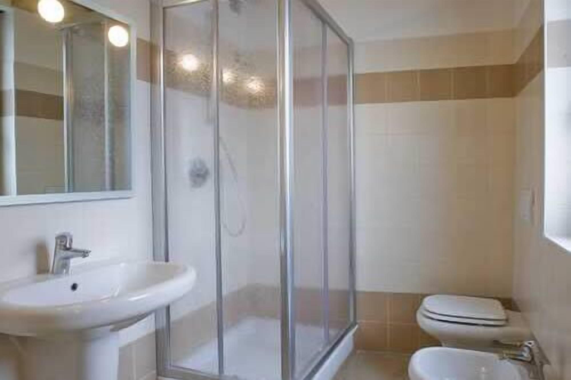 A bathroom with a glass shower enclosure, a sink, and a toilet.