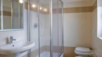 A bathroom with a glass shower enclosure, a sink, and a toilet.