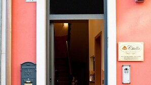 Entrada de un edificio con un cartel con el número '19', una puerta, una escalera que conduce al interior y una placa con el nombre 'Citella'.