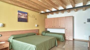 A room with two beds, wooden ceiling beams, a wall-mounted picture, and a wardrobe.