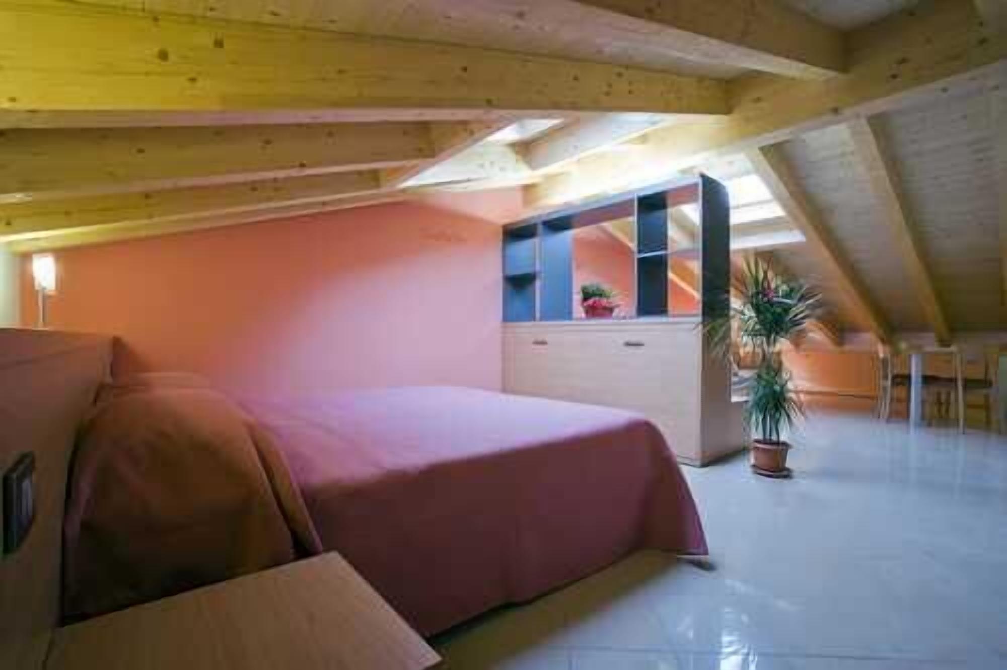 Une chambre à coucher avec un lit, une commode, une plante en pot et un plafond en pente.