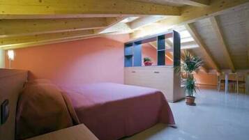 Une chambre à coucher avec un lit, une commode, une plante en pot et un plafond en pente.