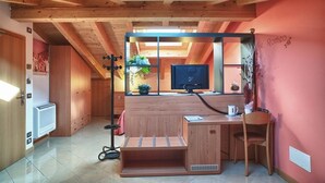 Una habitación compacta con escritorio de madera, una silla, televisor y ventana con vistas al exterior.
