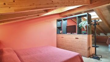 A bedroom with a wooden ceiling, a pink wall, a bed, a dresser, and a mirror.