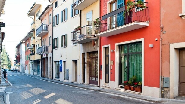 Una calle con edificios de colores, una vía despejada y un paso de peatones.