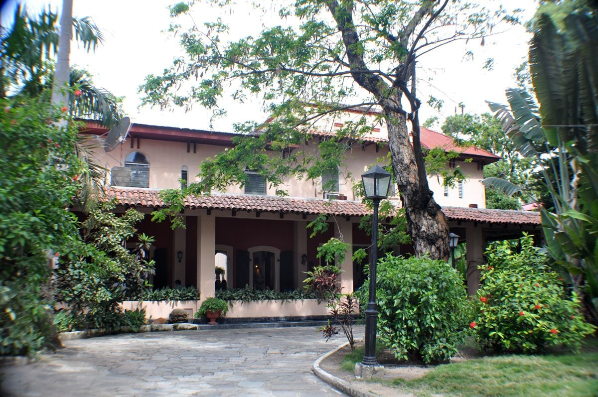 A building with a tiled roof, a covered entrance, and a garden area with potted plants and a pathway.