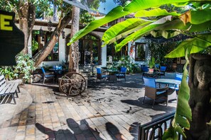 Un espace extérieur aménagé en patio, avec des sièges, une roue décorative et une végétation luxuriante.