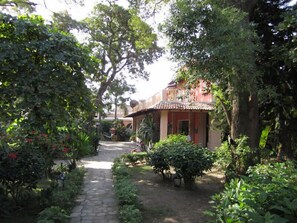 Un sentier de jardin qui mène à un bâtiment doté d’un toit en tuiles et d’une façade rouge.