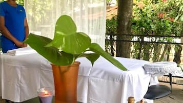 Enjoy a serene outdoor setting with a beautifully set table, featuring a vase, a plant, a candle, and a refreshing drink.