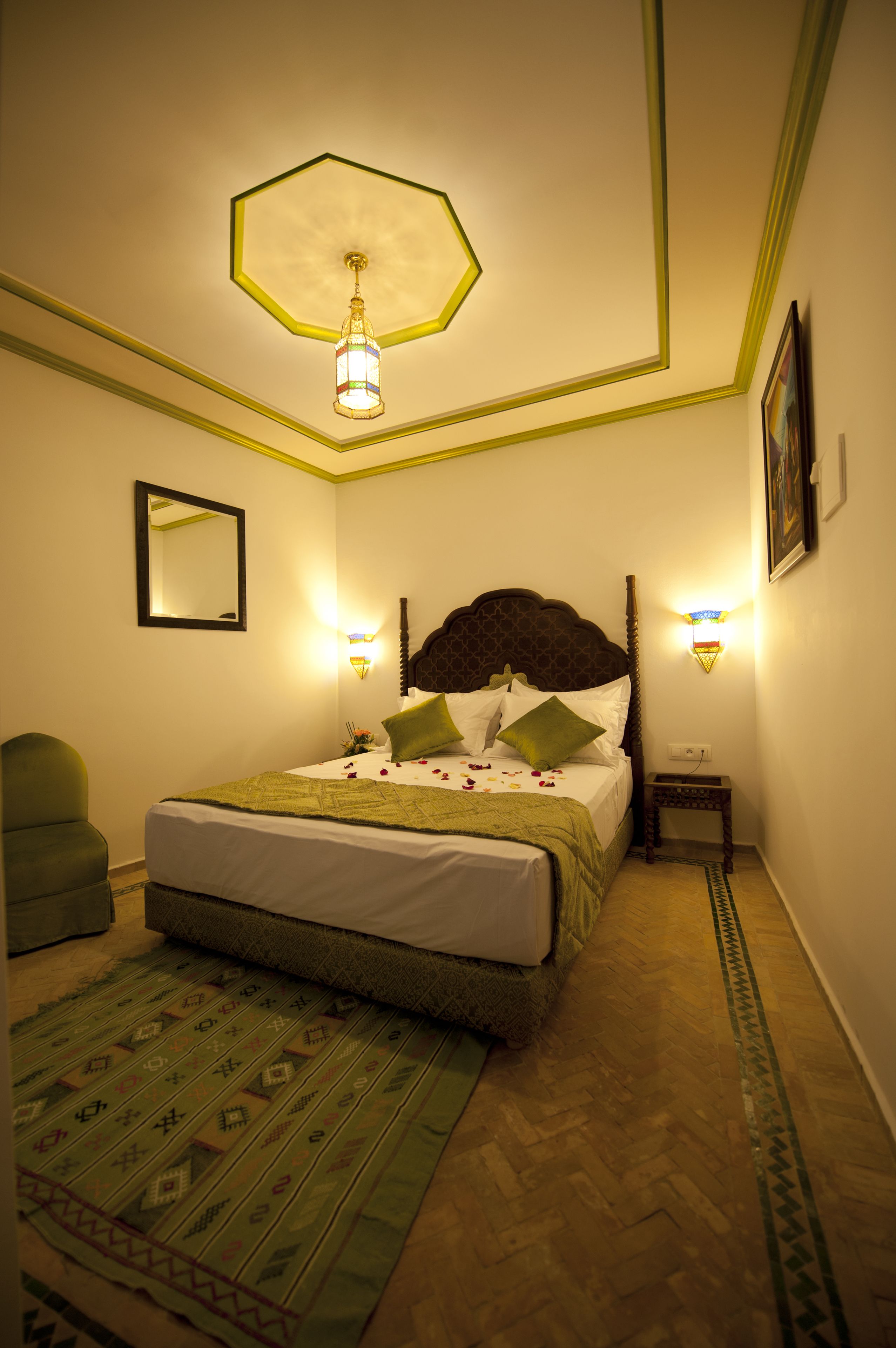 A neatly arranged bedroom with a bed, a chair, a nightstand, and a wall-mounted lamp.