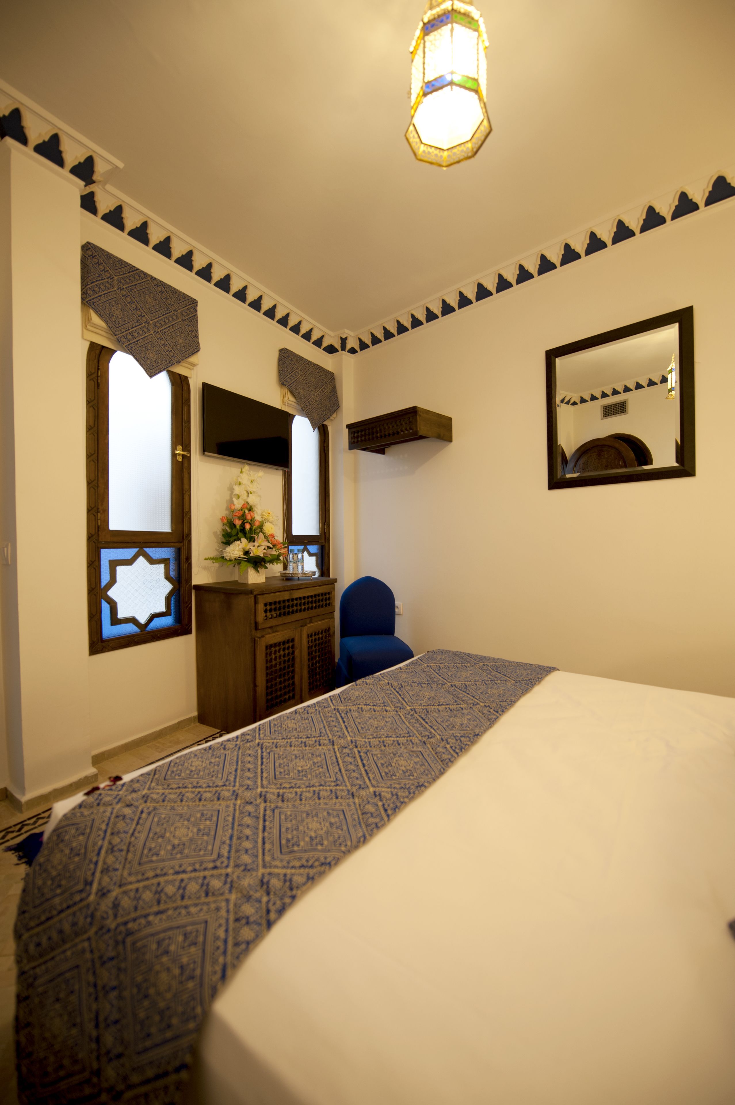 Una habitación de hotel con cama, un escritorio con espejo y un adorno en la pared.