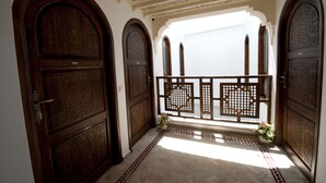 Un pasillo con puertas de madera decoradas y un techo ornamental.