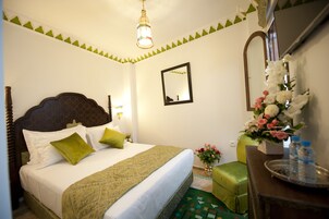 Habitación de hotel impecable con una cama grande, una mesita de noche con un florero y un espejo en la pared.