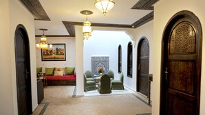 Un interior tradicional con un sofá, dos sillones, una mesa con un florero y una puerta decorativa.