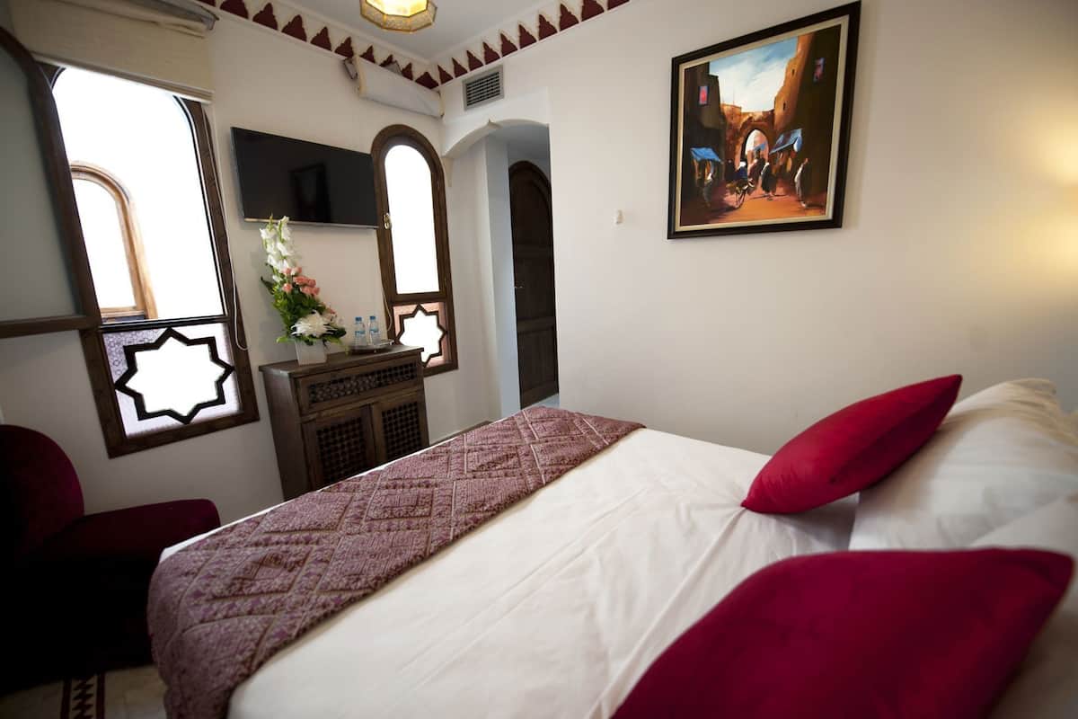 Una habitación de hotel con una cama, un escritorio, un espejo y un cuadro en la pared.