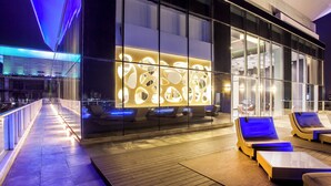 A modern hotel lobby with a glass facade, seating area with loungers, and a wooden floor. - Sortis Hotel, Spa & Casino, Autograph Collection by Marriott (Panama City)