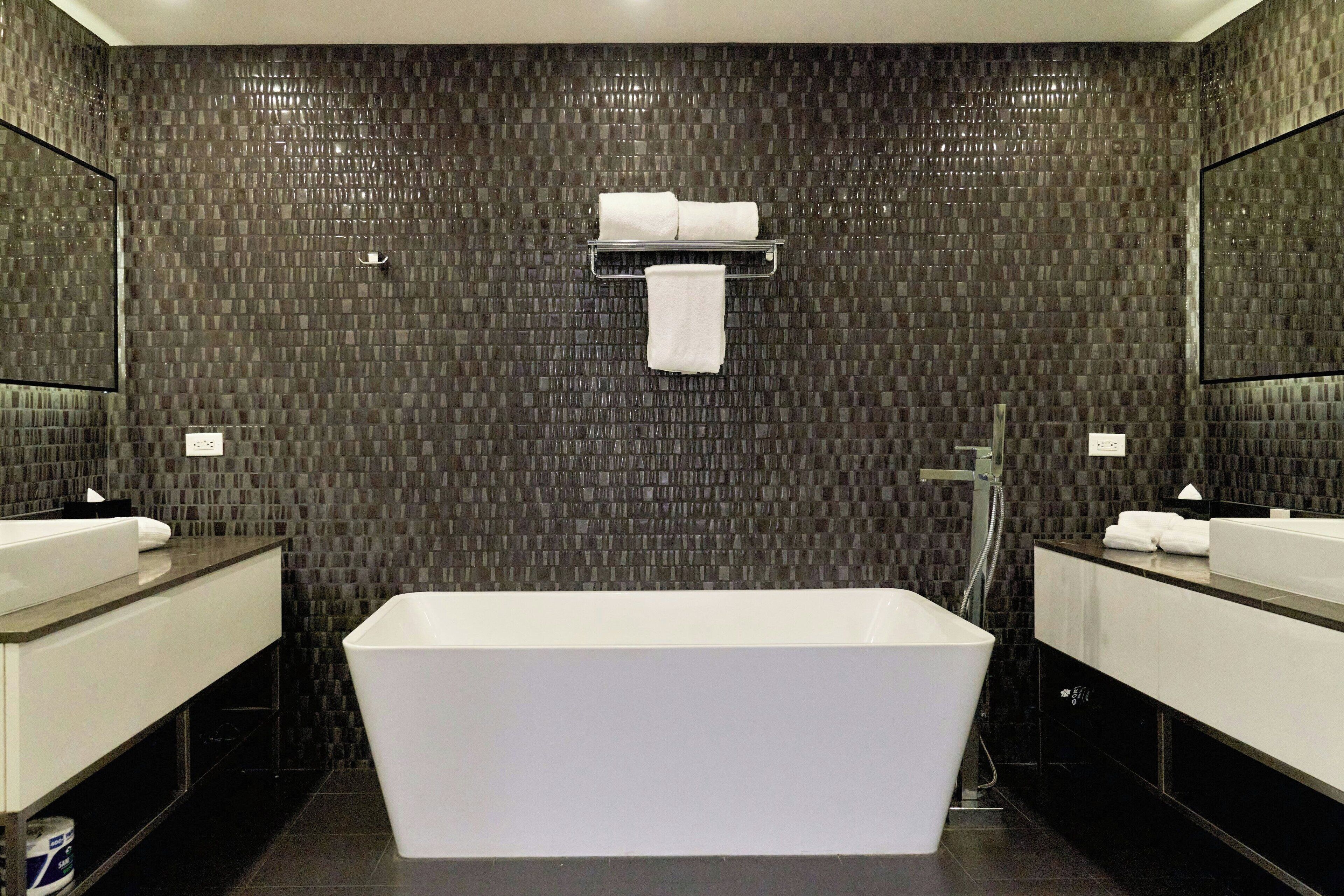 Un baño moderno con una bañera grande, dos lavamanos y un perchero para toallas.