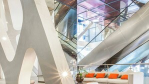 A modern interior with a large abstract sculpture, a staircase, a sofa with orange cushions, and a patterned rug. - Sortis Hotel, Spa & Casino, Autograph Collection by Marriott (Panama City)