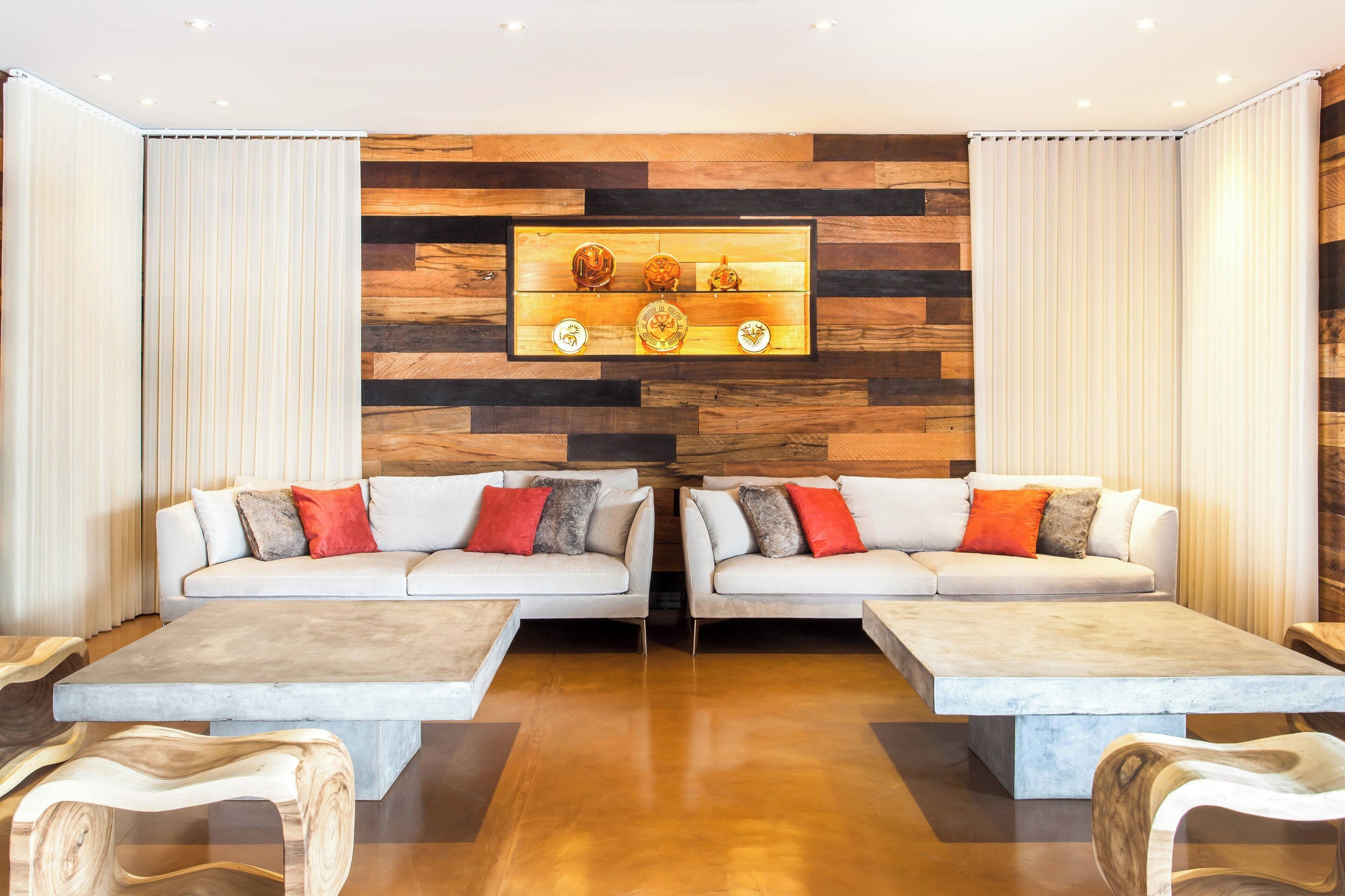 Una sala de estar moderna con dos sofás, una mesa de centro y una pared de madera con un estante que exhibe objetos decorativos.