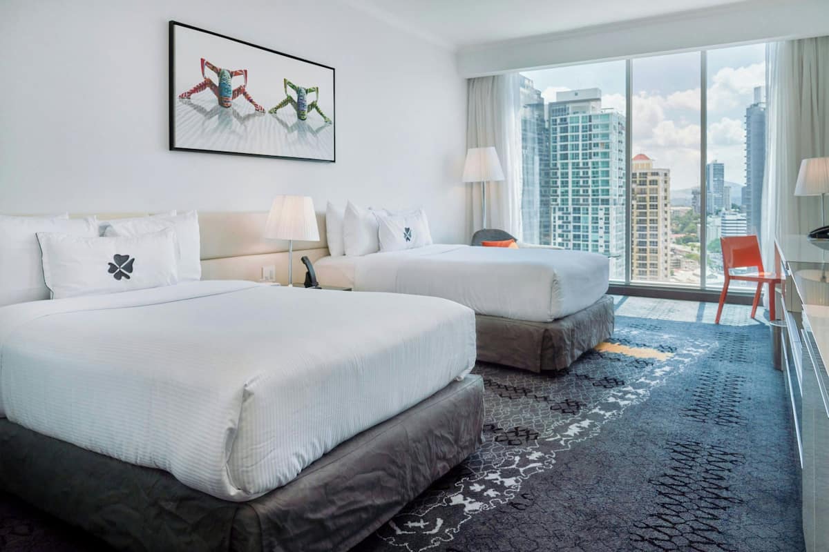 A hotel room with two beds, a large window with a city view, and a modern design.