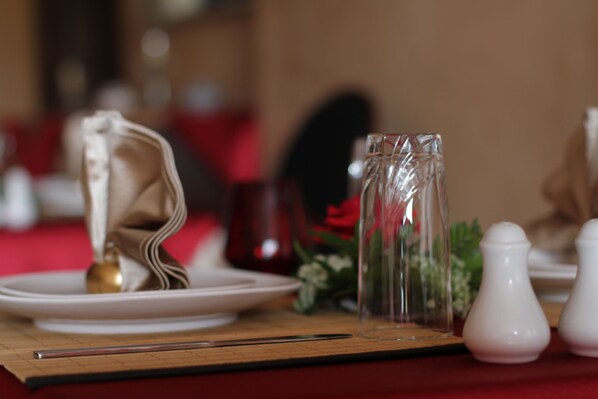 Una mesa dispuesta con platos blancos, una jarra de vidrio transparente y saleros y pimenteros blancos.
