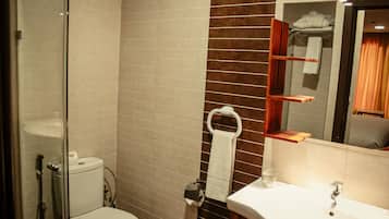 A bathroom with a toilet, sink, and glass shower enclosure.