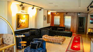 A modern living room with a sectional sofa, a tufted ottoman, and a red carpet. - Hôtel Belle Vue & Spa (Meknes)