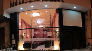 A hotel entrance with a curved facade, glass doors, and a reception area with seating. - Hôtel Belle Vue & Spa (Meknes)
