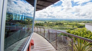 A balcony with a glass railing overlooking a green landscape and a clear sky. - Hotel Sonesta Pereira (Pereira)