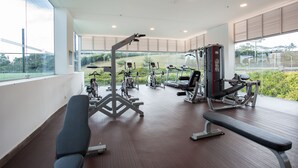 A spacious gym with various exercise equipment, large windows offering views of greenery, and a wooden floor. - Hotel Sonesta Pereira (Pereira)
