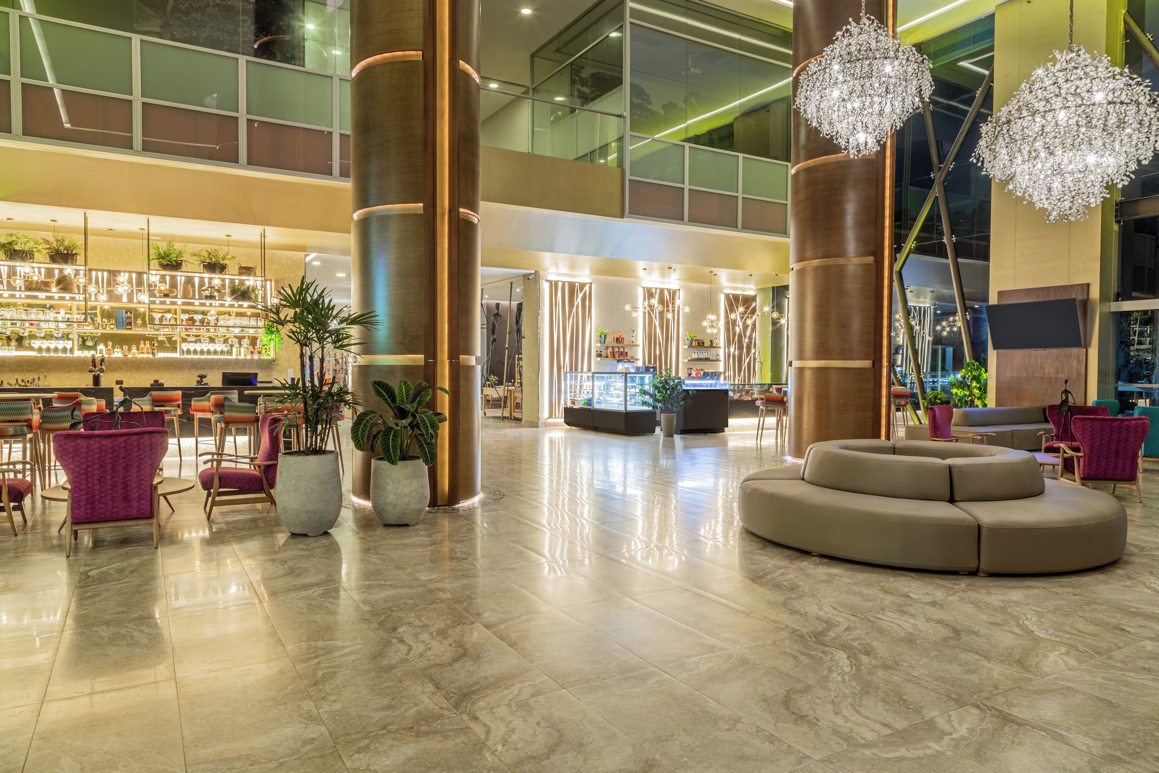 Un hall espacioso con zona de bar, arreglos de asientos y grandes lámparas decorativas.