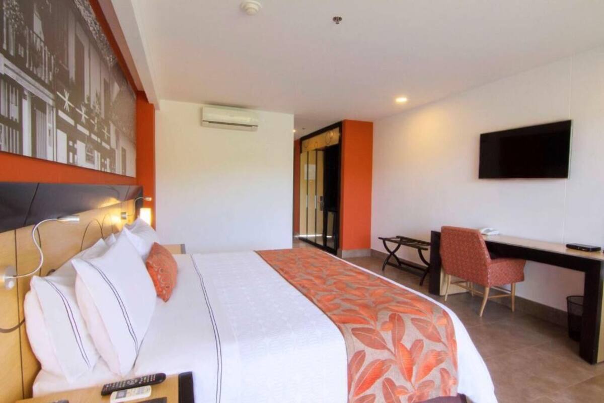 Une chambre d’hôtel équipée d’un lit, d’un bureau, d’une chaise, d’une télévision et d’un appareil de climatisation.