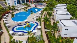 Un complexe hôtelier doté de plusieurs piscines, de chaises longues et d’un espace de jeux pour enfants.