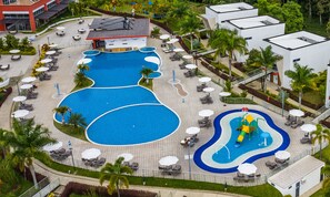 Relax by the expansive pool complex, featuring multiple interconnected pools and lounge areas with shaded seating.