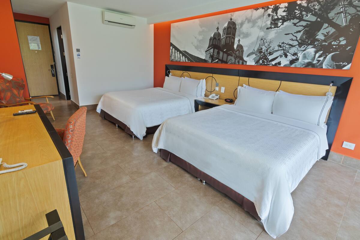 Une chambre d’hôtel avec deux lits, un bureau avec un téléphone et une chaise.