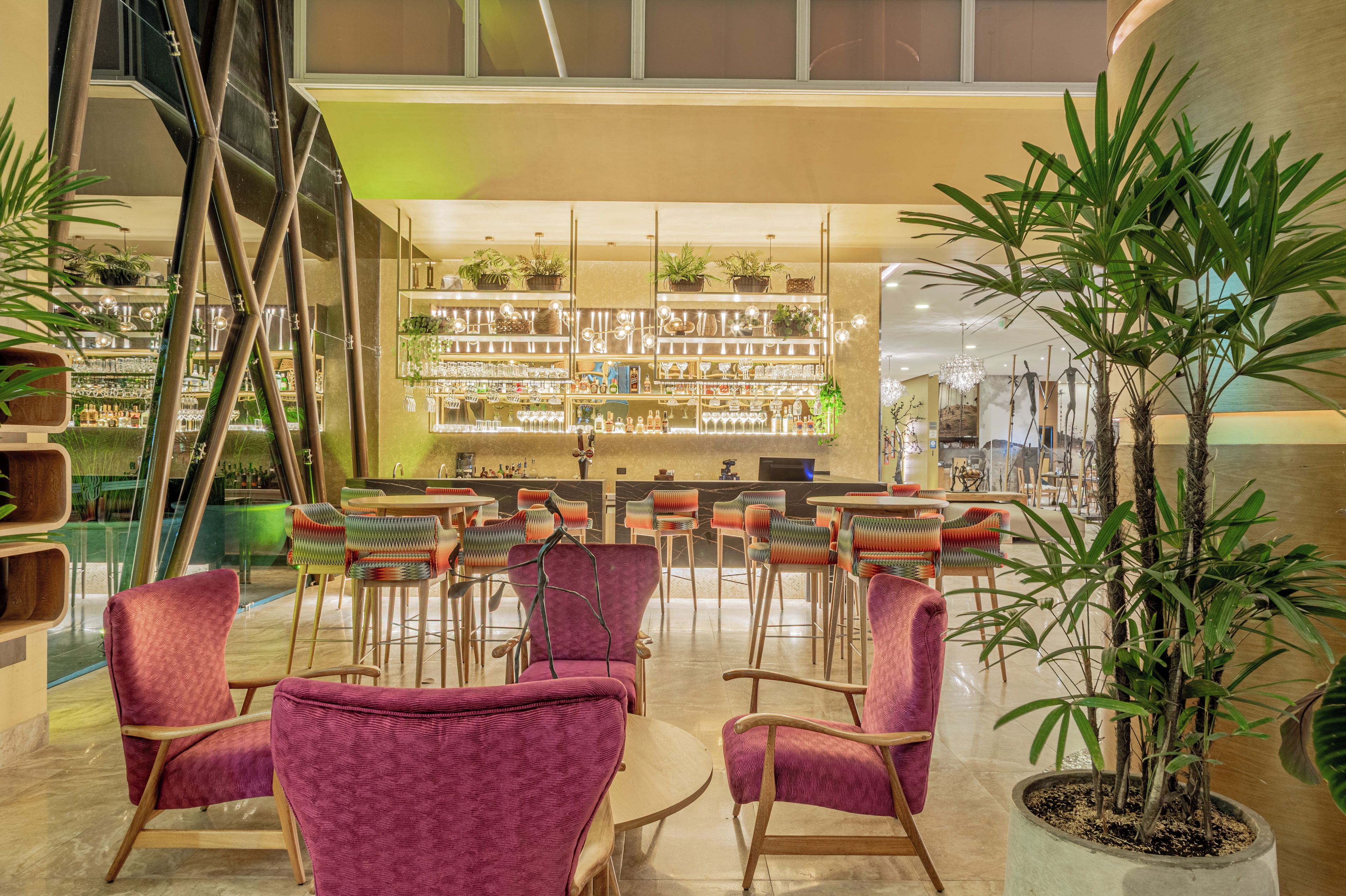 A bar area with seating and a variety of bottles and glasses on shelves.