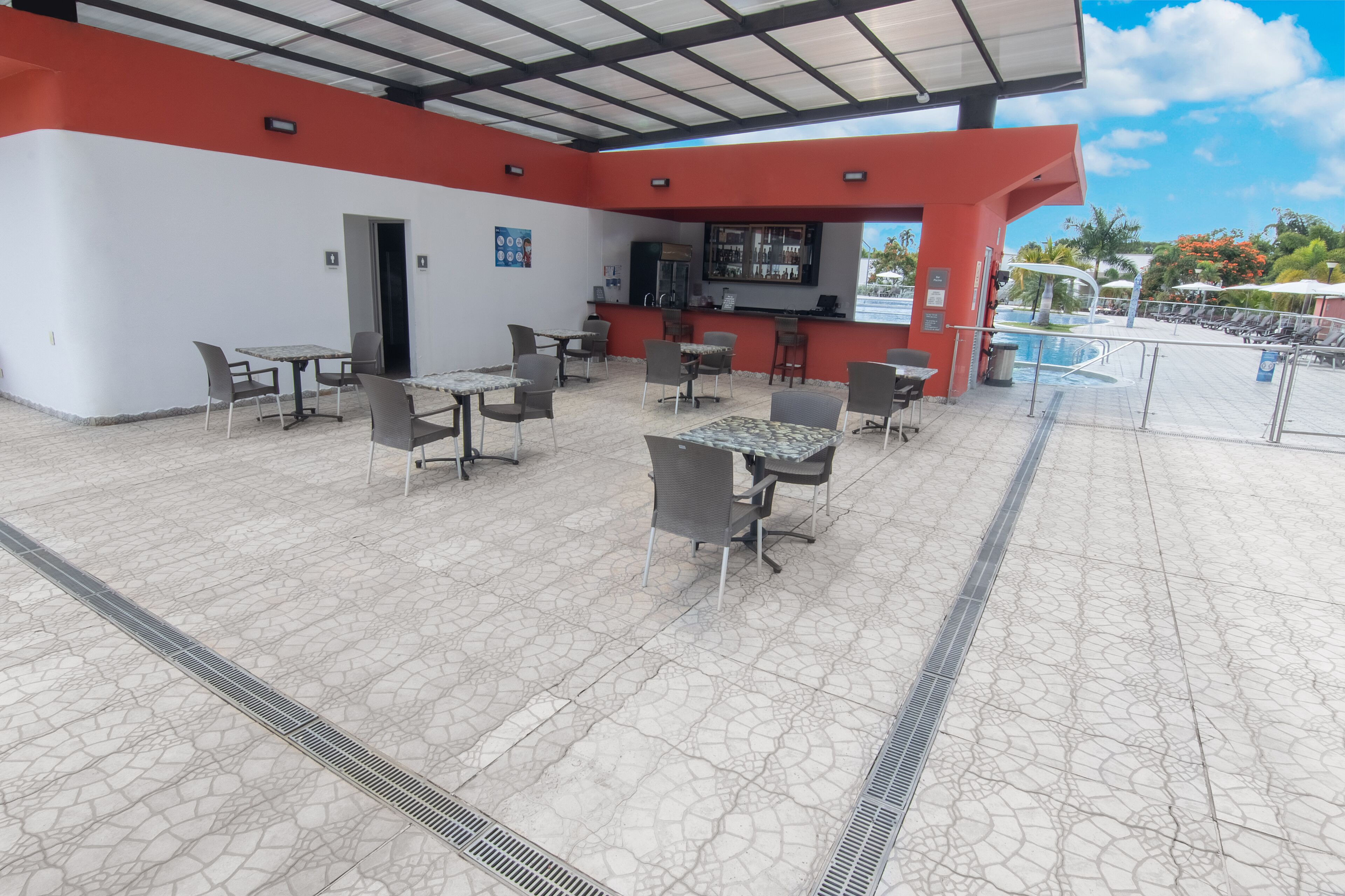 Eine Außenpatio-Terrasse mit Tischen, Stühlen, einer Bar und einem Pool.