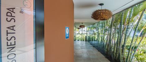 Un pasillo con un cartel que indica 'Sonesta Spa' y vistas de plantas de bambú.