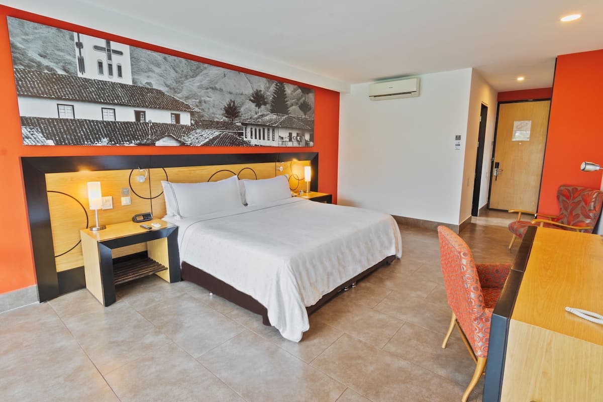 Une chambre d’hôtel comprenant un lit, des tables de chevet, un bureau, une chaise et une grande fresque murale.