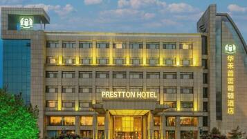 A modern hotel with a prominent entrance, multiple floors, and a clear sky.