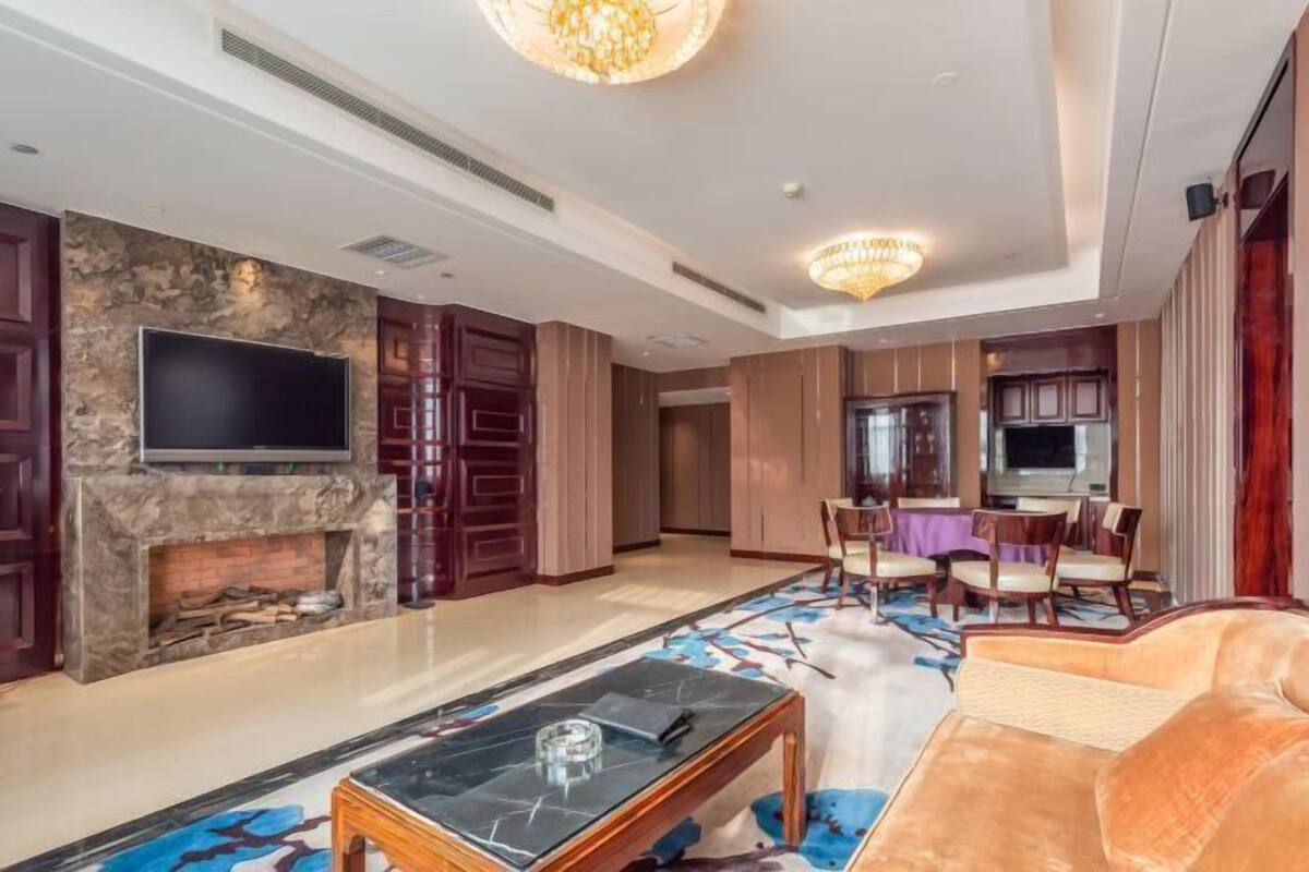 A spacious living room with a fireplace, a flat-screen TV, a dining area, and a plush sofa.