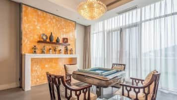 A room with a pool table, wooden chairs, a chandelier, and a fireplace.